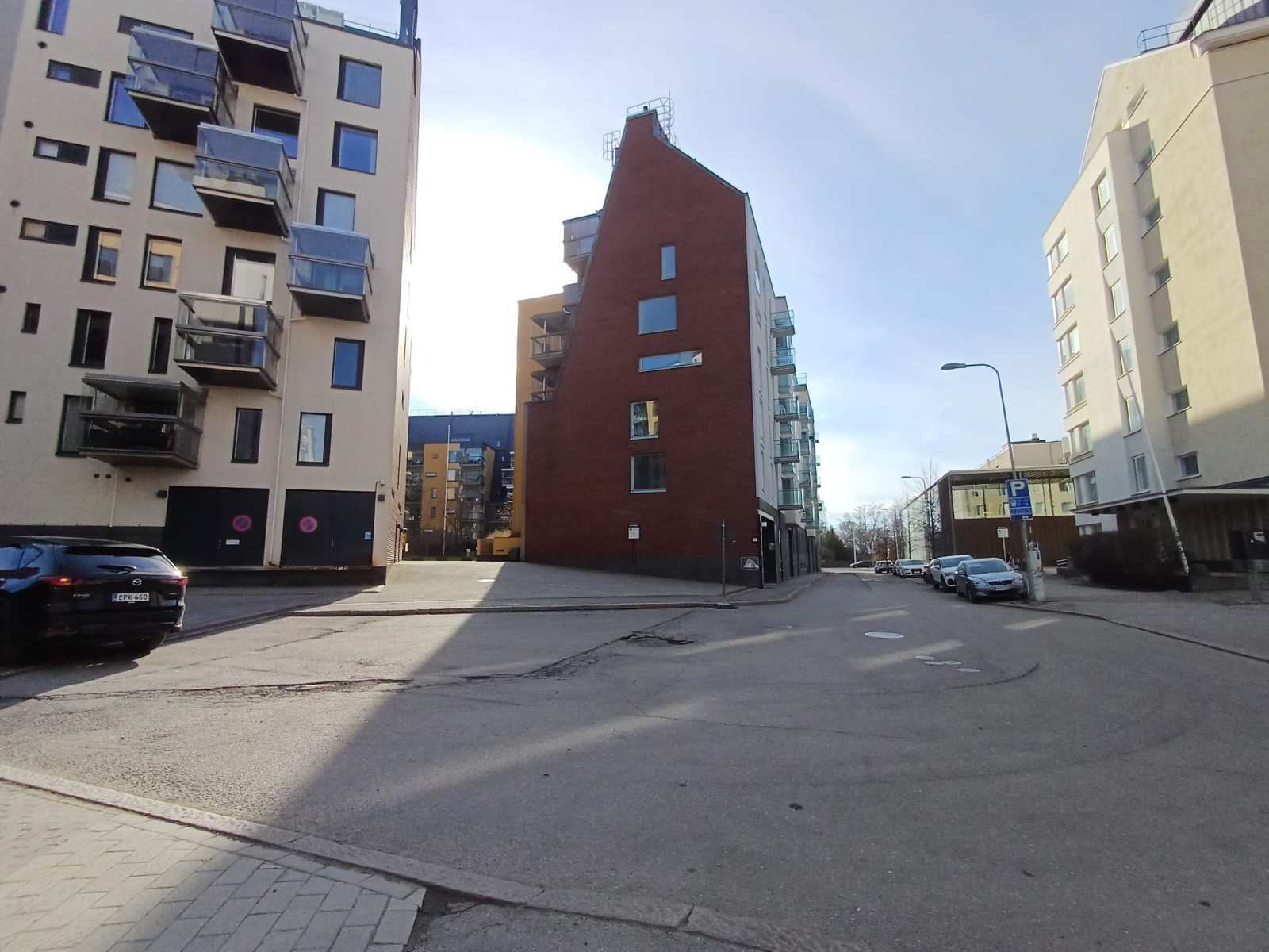 A crossroads with a red-brick apartment building in the middle. To its right, further along the street, the low brown Domus Gaudium is visible.